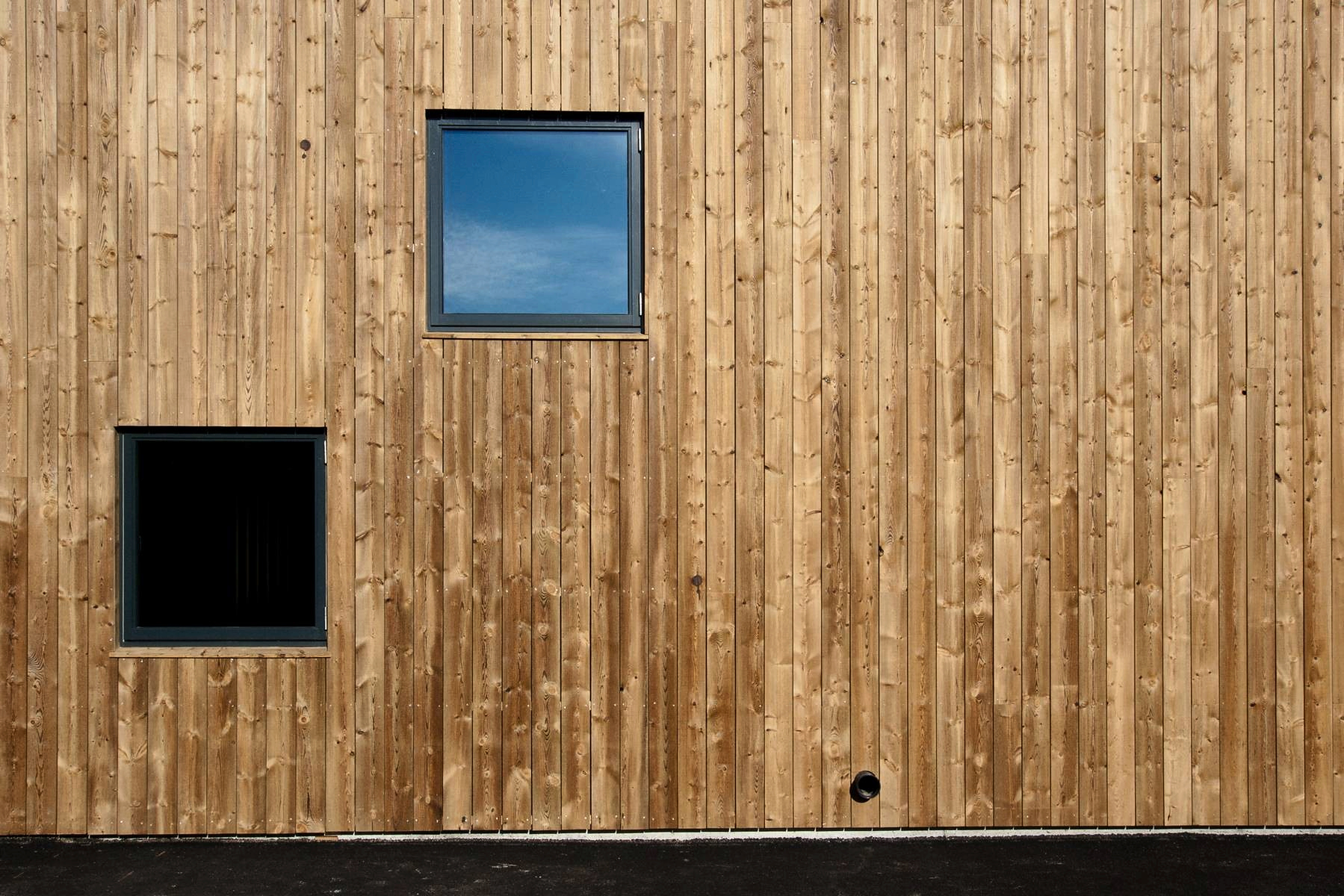 Vertikale Holzfassade mit unterschiedlich großen Fensteröffnungen